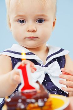 A little sweet girl with a cake and a candle in her first birthday.