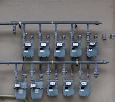 Ten Gray Gas Meters on the wall of an apartment building