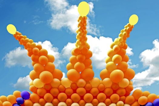 Crown from orange balloons against a blue sky