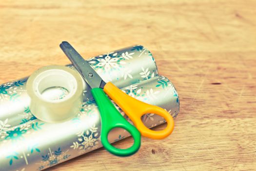 Scissors, tape and wrapping paper on a wooden table