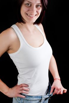 attractive caucasian woman with big jeans on black background, weight loss