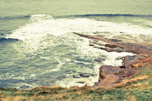 Rough sea crashing against coastal rocks in Scotland