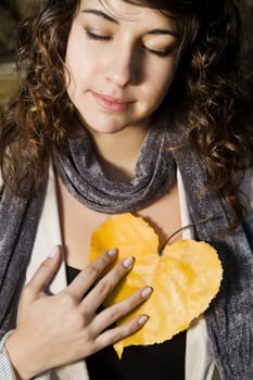 View of a beautiful girl on a urban park with a yellow leaf.