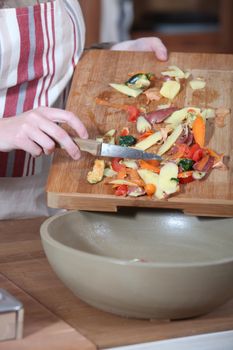 Women removing vegetables peeling from chopping board