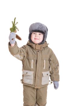 a smiling boy dressed for winter with a branch of fur tree with cones