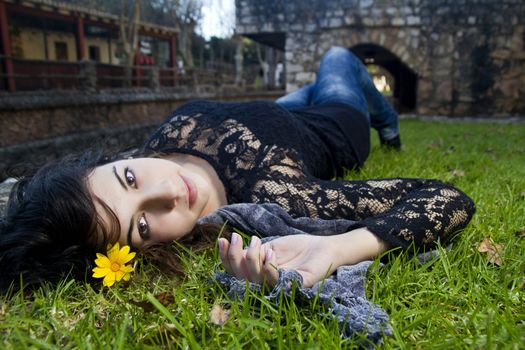 Beautiful young girl lies down on the green grass on a urban park.