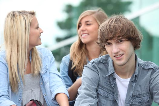 Three students sitting outside on some steps