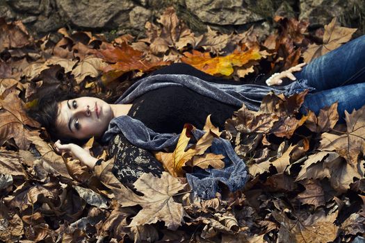 View of a beautiful girl in the middle of autumn leaves.