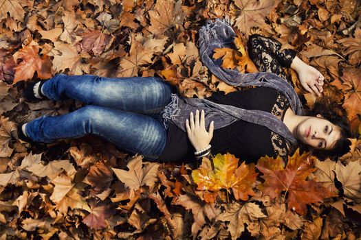 View of a beautiful girl in the middle of autumn leaves.