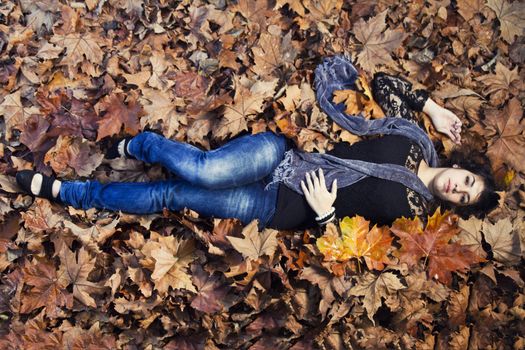 View of a beautiful girl in the middle of autumn leaves.