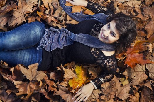 View of a beautiful girl in the middle of autumn leaves.