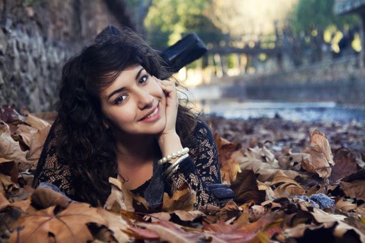 View of a beautiful girl in the middle of autumn leaves.