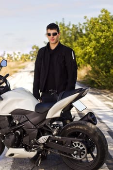 View of a man with a motorcycle on a asphalt road.