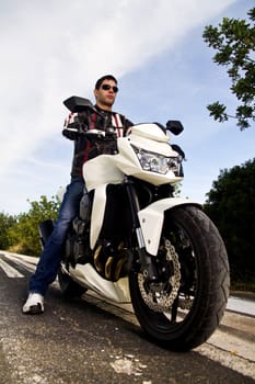View of a man with a motorcycle on a asphalt road.