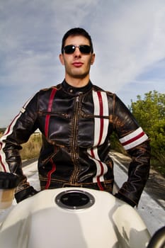 View of a man with a motorcycle on a asphalt road.