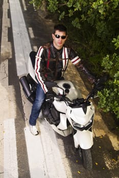 View of a man with a motorcycle on a asphalt road.