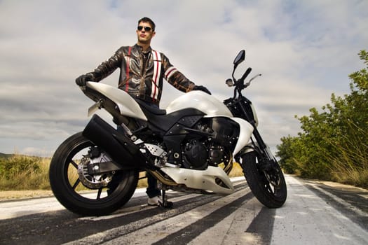 View of a man with a motorcycle on a asphalt road.