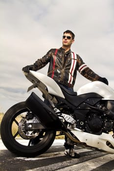 View of a man with a motorcycle on a asphalt road.