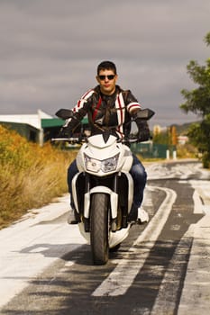 View of a man with a motorcycle on a asphalt road.
