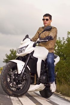 View of a man with a motorcycle on a asphalt road.