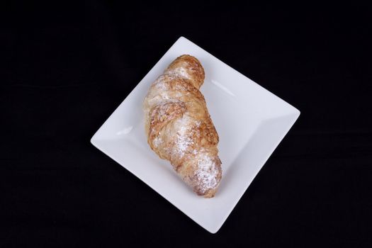 fresh almond croissant isolated on a black background