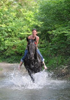 young woman and her black stallion in a river