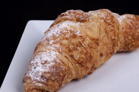 fresh almond croissant isolated on a black background