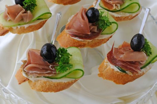 Mini sandwiches with ham and cucumber on a baguette