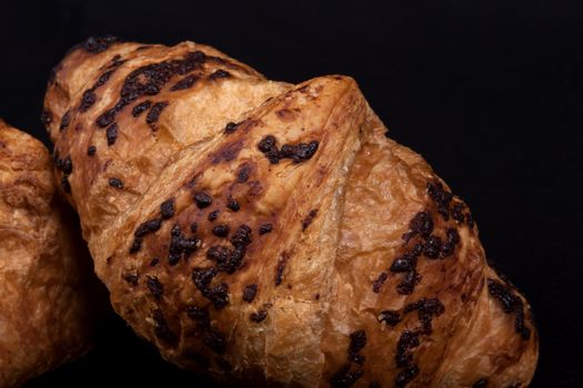 fresh chocolate croissant isolated on a black background