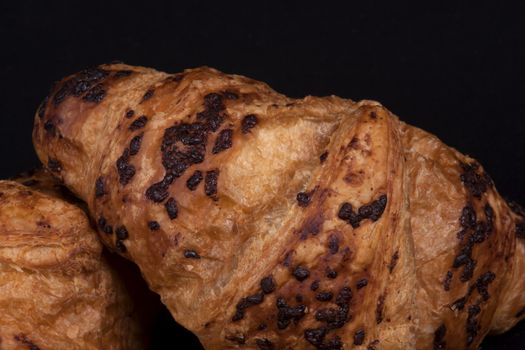 fresh chocolate croissant isolated on a black background