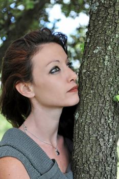 beautiful young woman near a trunk of tree