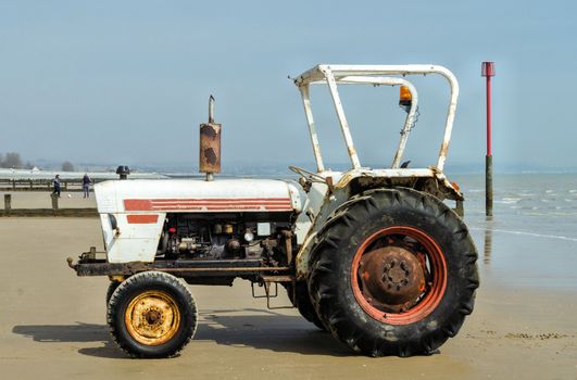 White tractor on a beac ready to pull small boats ashore