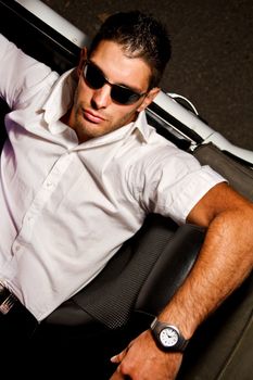 View of a young male next to his white convertible car.
