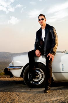 View of a young male with a jacket next to his white convertible car.