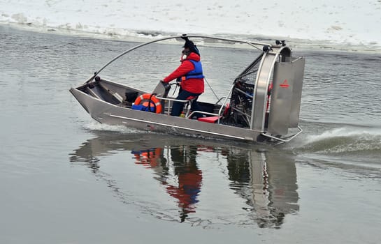 Airboat on the river in the winter time. Two guards inside. Faces unrecognizable.
