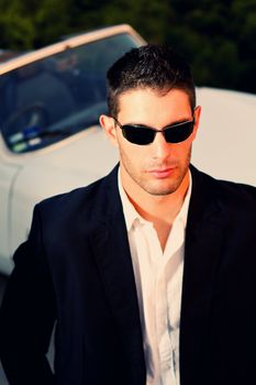 View of a young male next to his white convertible car.