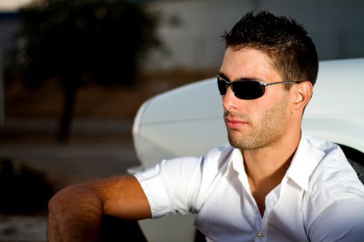 View of a young male next to his white convertible car.