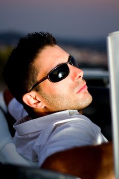 View of a young male next to his white convertible car.