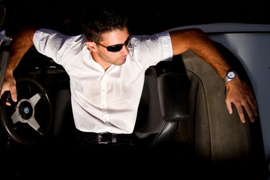 View of a young male next to his white convertible car.