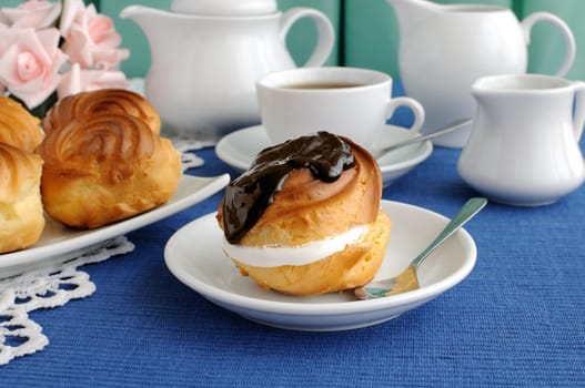 Éclair with chocolate, close-up on a plate with a cup of coffee