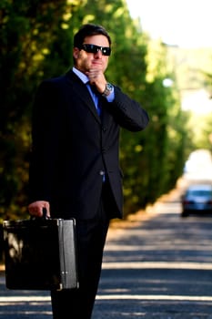 View of a young male business man on a asphalt road.