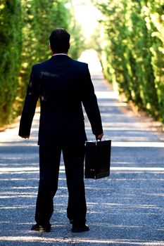 View of a young male business man on a asphalt road.