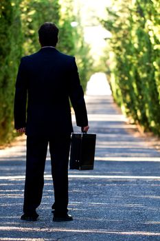View of a young male business man on a asphalt road.