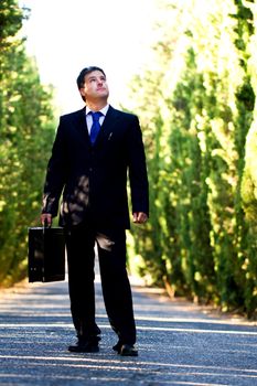 View of a young male business man on a asphalt road.