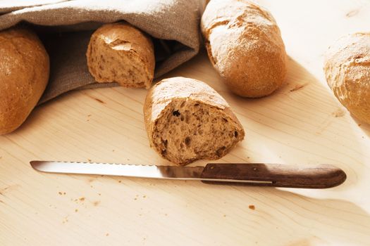 broken rye bun with a knife in front of other rye buns