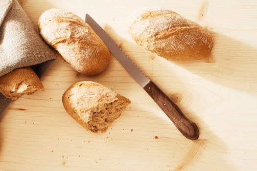 rye buns from top with a linen textile a knife and wooden background