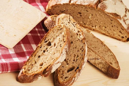 rustic sliced bread with a towel from top on wooden background with a chopping board