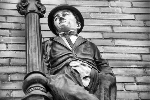 Figure of actor Charlie Chaplin with bowler hat, wall in background