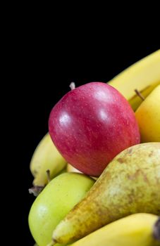 Red apple on assorted fruits with a black background