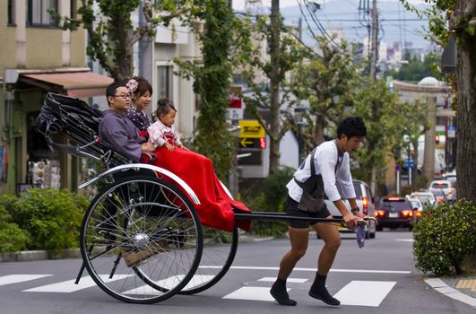 KYOTO , JAPAN - OCT 24 : Japanese family on a trditional rickshaw being pulled by a man on October 24 2009 in Kyoto , Japan